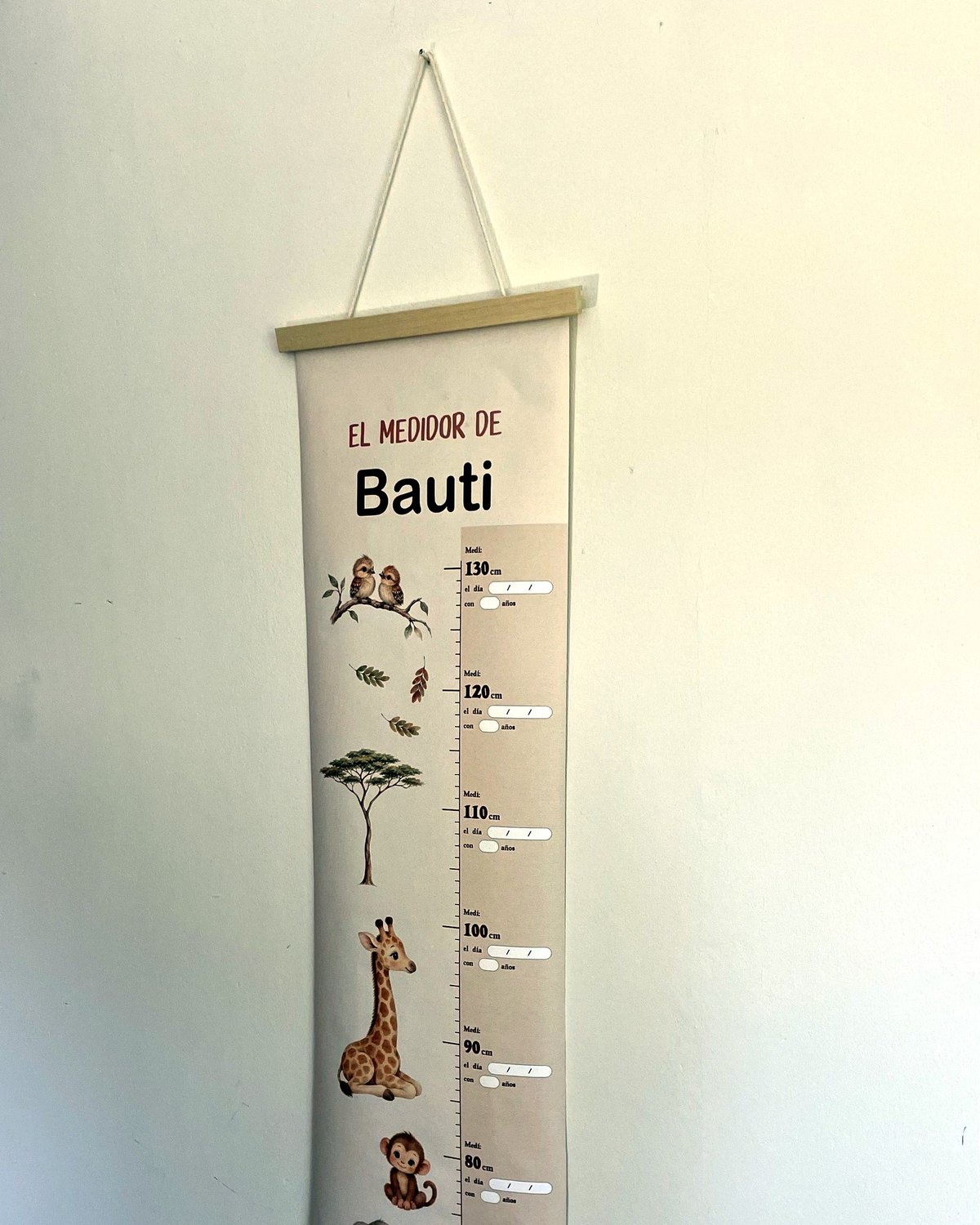 Medidor de altura Safari con el nombre Bauti colgado en la pared